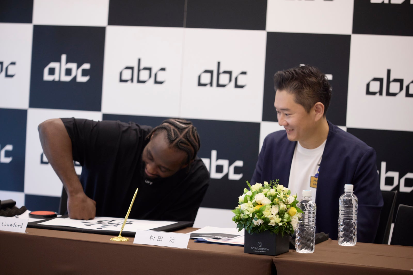 Terence Crawford signing the memorandum of understanding with his fist in ink, beside Gen Matsuda, at the Crawford Production Japan signing ceremony